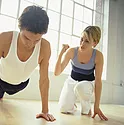 A man doing a push-up while a woman encourages him on.